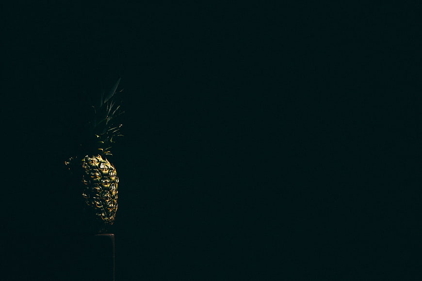 Dark moody pineapple on pedestal with large negative space