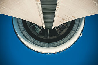 Low angle view of modern circular concrete tower against blue sky