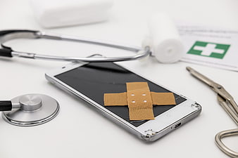 Broken Smartphone with Medical Bandage and Stethoscope