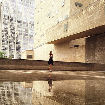 Woman in Black Dress Standing on Wet Concrete with Reflection
