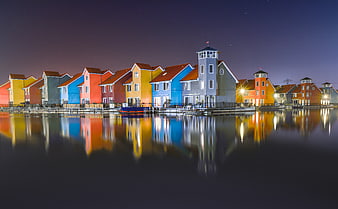 Colorful waterfront houses reflecting in calm water at night