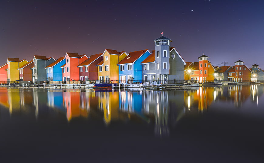 Colorful waterfront houses reflecting in calm water at night