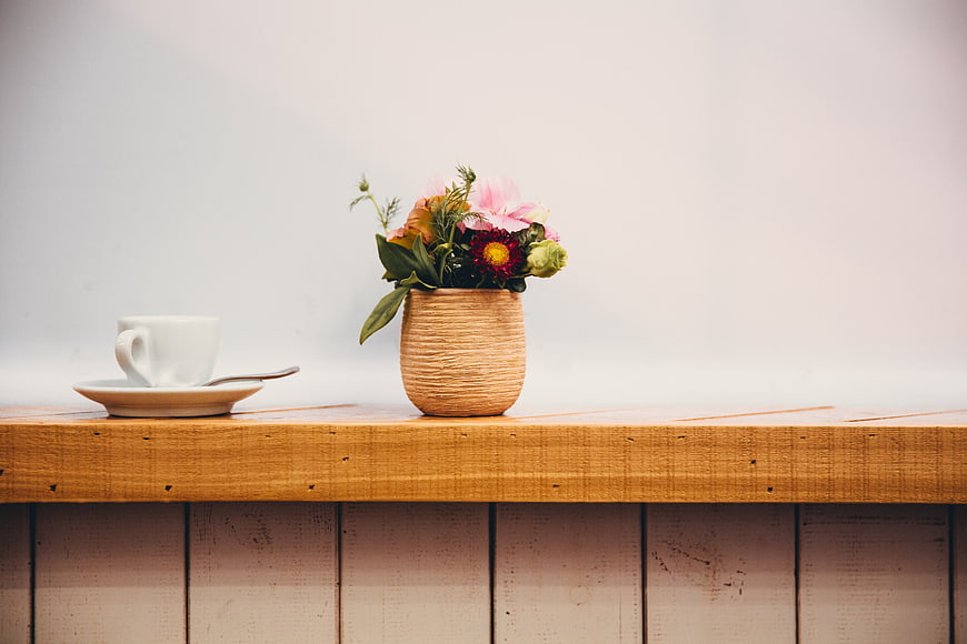 White Coffee Cup and Flowers on Wooden Shelf
