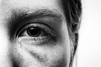 Black and white close-up of a crying eye with a tear