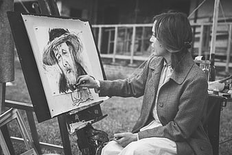 Woman sketching portrait on easel outdoors in black and white