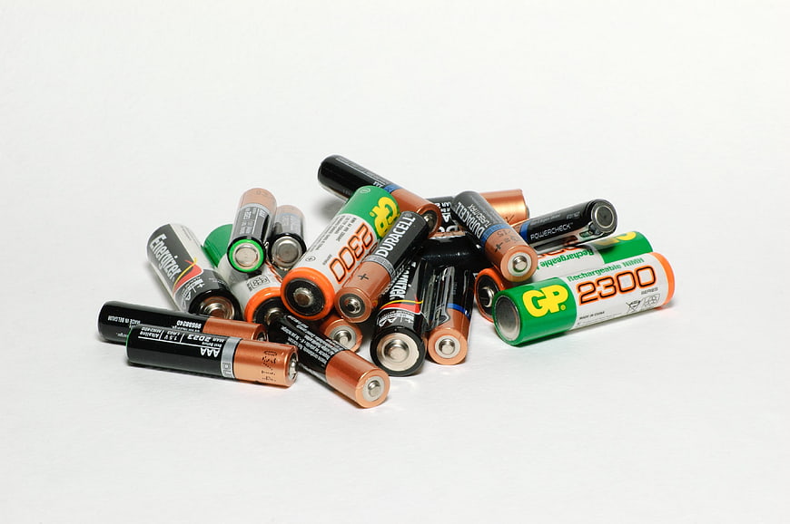 Assorted AA and AAA Batteries Piled on White Background