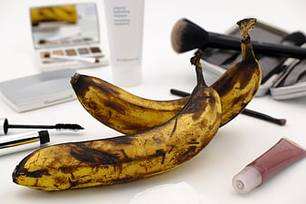 Overripe Bananas and Makeup Products on White Surface