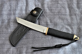 Tanto combat knife with leather sheath on gray fabric