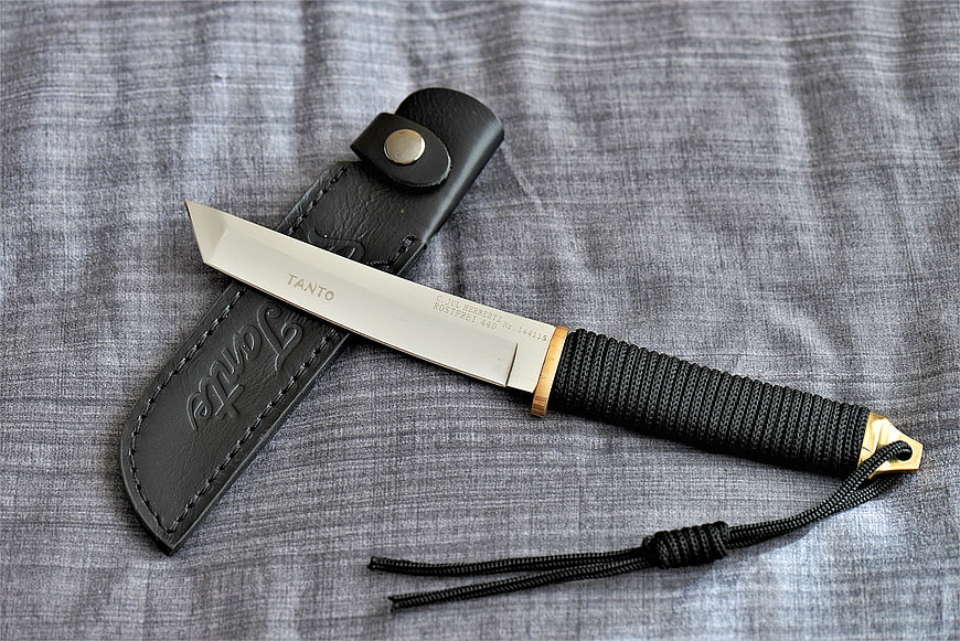 Tanto combat knife with leather sheath on gray fabric