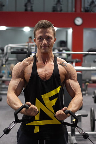 Muscular man performing cable fly exercise in gym