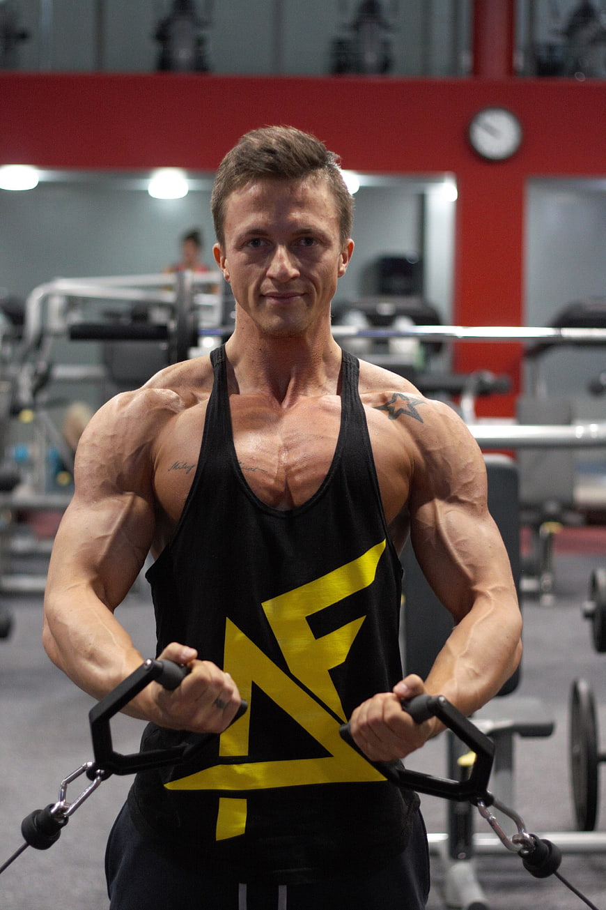 Muscular man performing cable fly exercise in gym