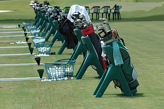 Golf bags and clubs lined up at a driving range
