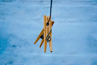 Wooden Clothespin Hanging on Black Rope Against Blue Background