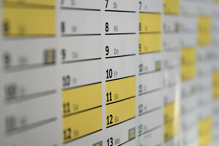 Close-up of wall calendar with yellow highlighted dates