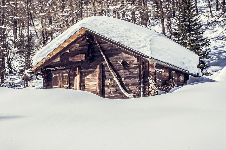 Rustic wooden cabin buried in deep snow in winter forest