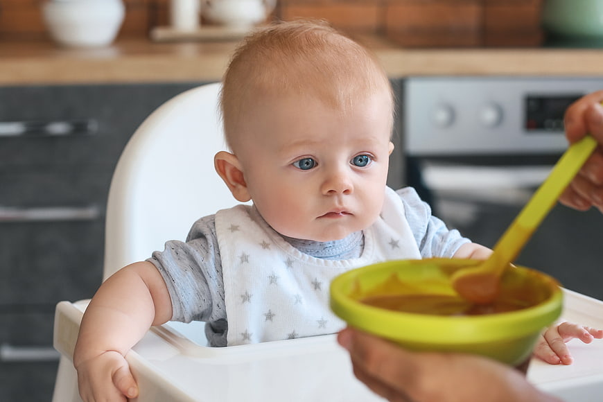 Baby in High Chair Being Fed Puree
