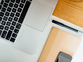 Flat lay of laptop, notebook, pen, and smartphone on wooden desk