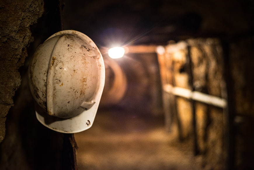 Dirty white hard hat hanging in dark underground mine tunnel