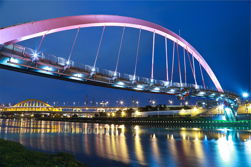 Illuminated Pink Arch Bridge Over River at Night