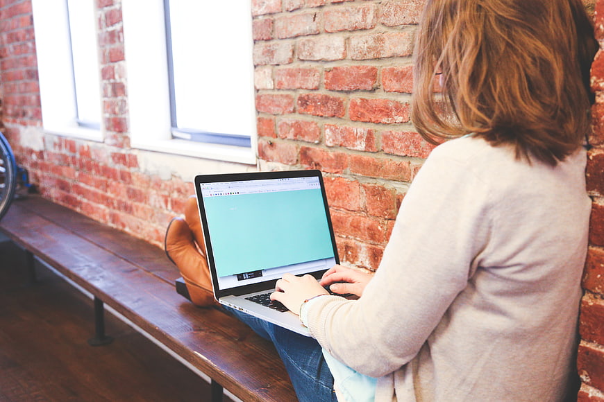 Woman typing on laptop in loft workspace