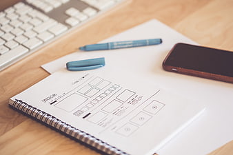 Hand-drawn wireframe sketches in a notebook on a wooden desk