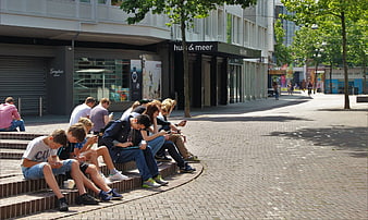 Teenagers sitting on steps using smartphones in city