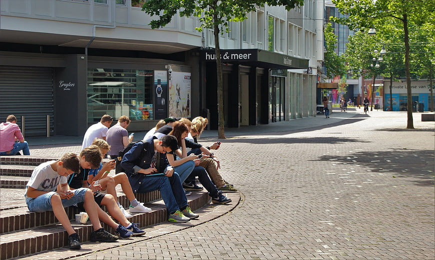 Teenagers sitting on steps using smartphones in city