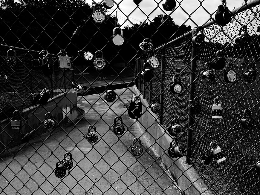 Black and white photo of love locks on a chain link fence
