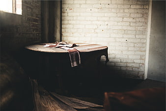 Vintage wooden table with cloth in rustic brick room
