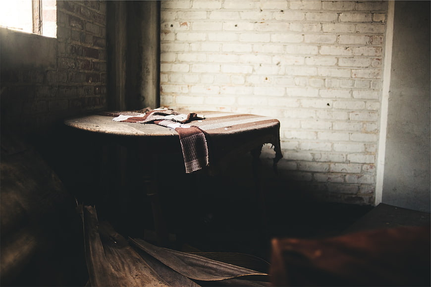Vintage wooden table with cloth in rustic brick room