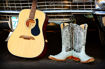 Acoustic Guitar And Cowboy Boots Leaning Against Vintage Cadillac Front Grille