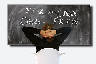 Student sitting in front of chalkboard with calculus formulas