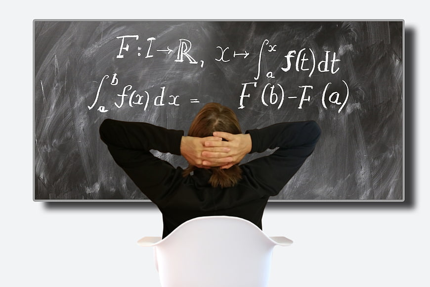 Student sitting in front of chalkboard with calculus formulas