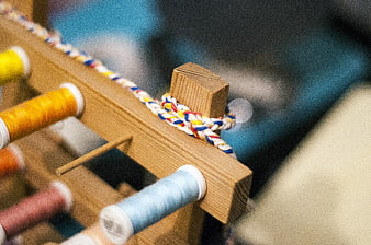 Close-up of wooden weaving loom with colorful thread spools