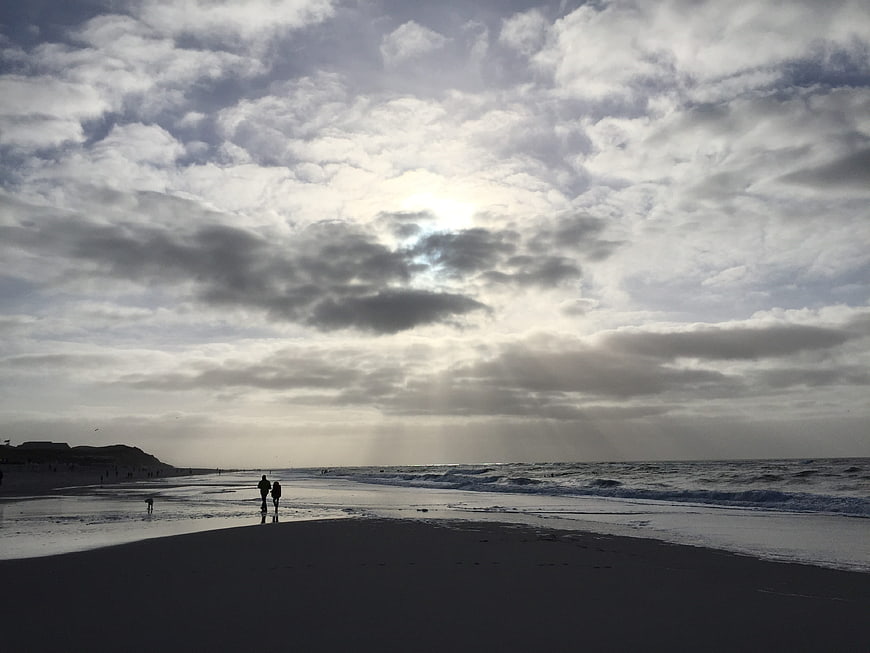 Silhouetted Couple Walking on Beach with Dramatic Cloudy Sky