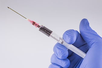 Blue Gloved Hand Holding Medical Syringe with Needle