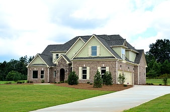 New suburban brick home with green siding and driveway