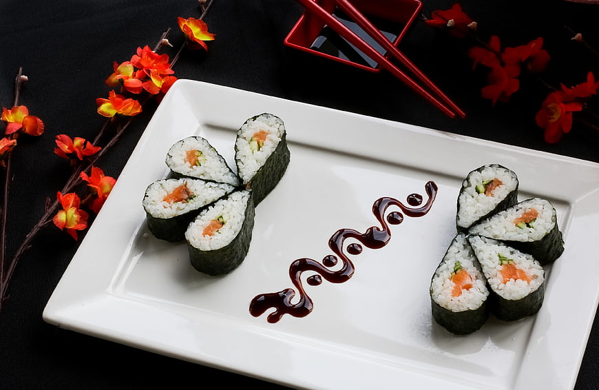 Artistically Arranged Salmon Sushi Rolls On White Plate