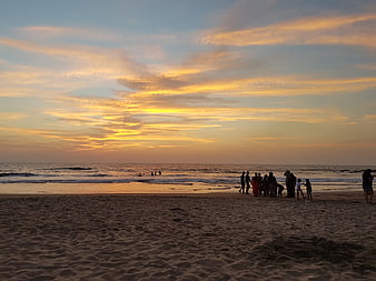 Silhouetted Group on Sandy Beach at Golden Sunset
