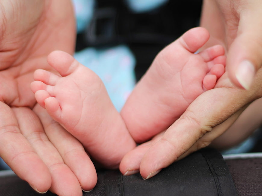 Close-up of baby feet held in adult hands