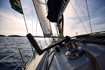 Sailing boat deck view with winch and sails on open water