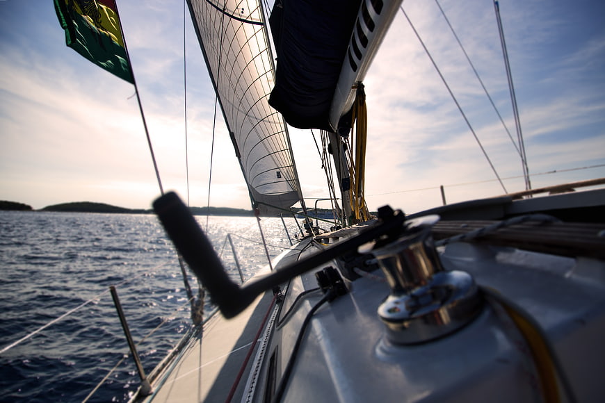 Sailing boat deck view with winch and sails on open water