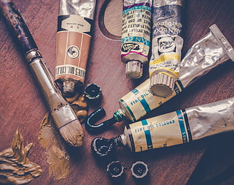 Oil paint tubes and brush on wooden table