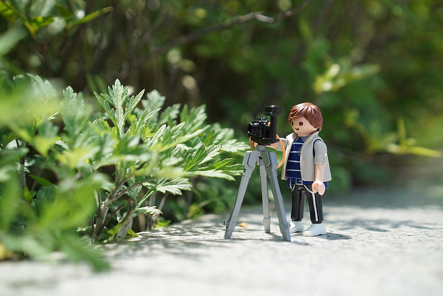 Playmobil Photographer Figure With Camera On Tripod Among Green Foliage