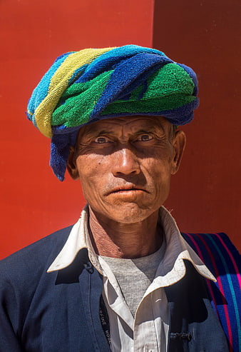 Portrait of elderly man in colorful turban against red wall