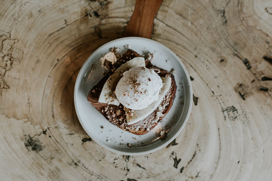 Overhead view of chocolate toast with banana and ice cream on rustic wood