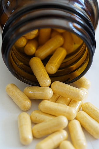 Yellow Vitamin Capsules Spilling From Amber Glass Bottle