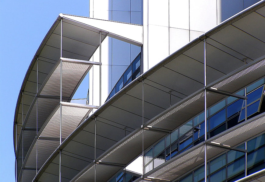 Modern curved office building with glass facade and metal sunshades