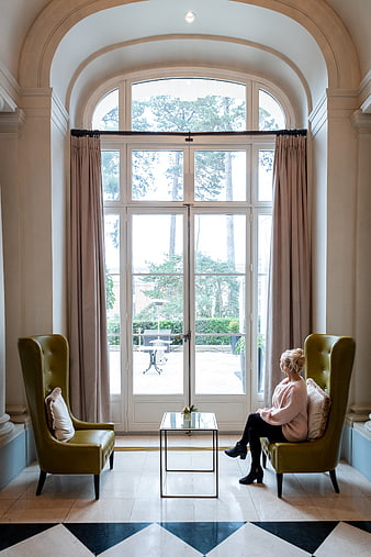 Woman relaxing in elegant hotel lobby with arched window