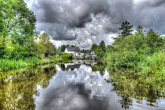 Cottage on River Bank Under Stormy Clouds
